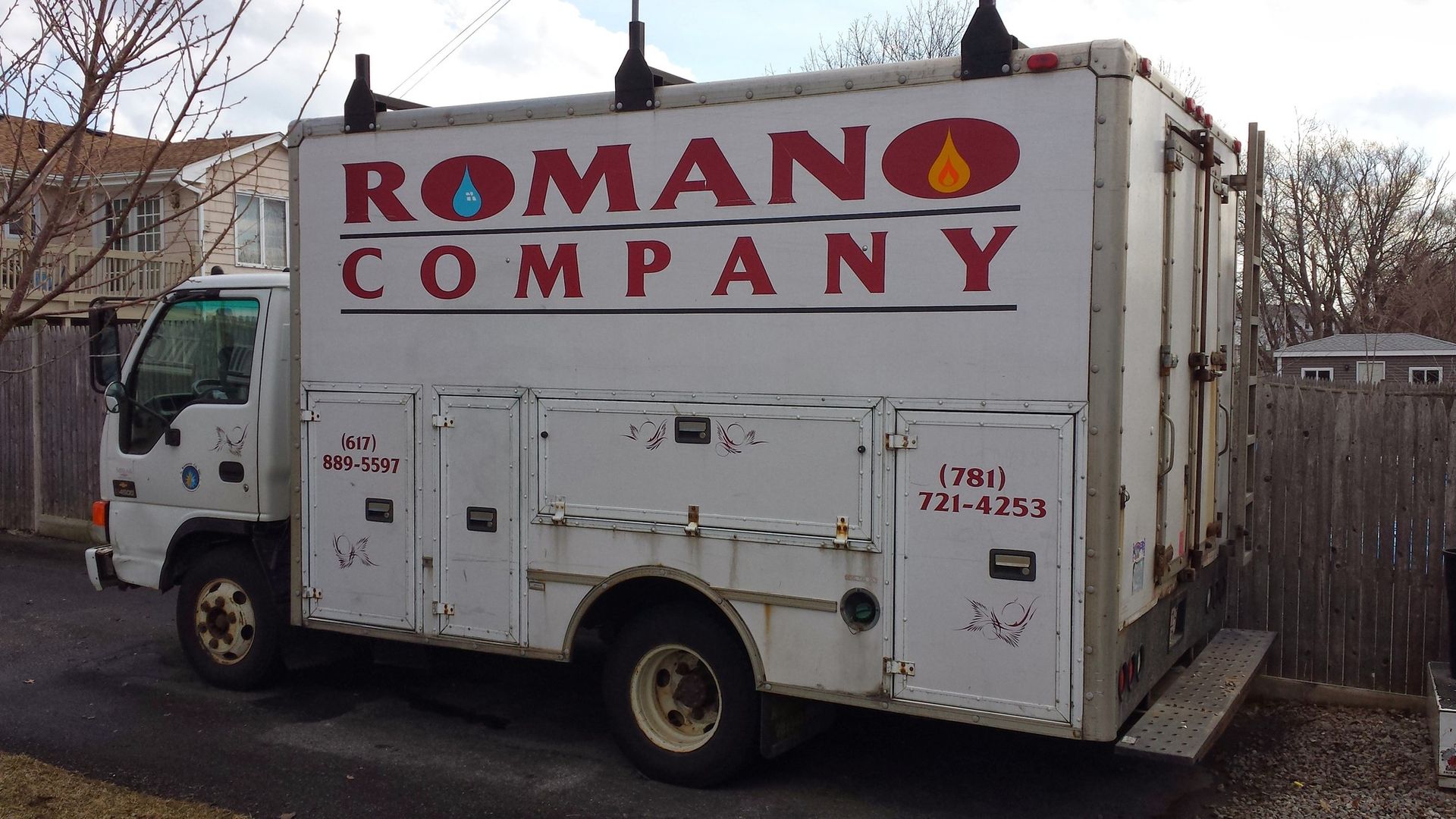 A white romano company truck is parked on the side of the road