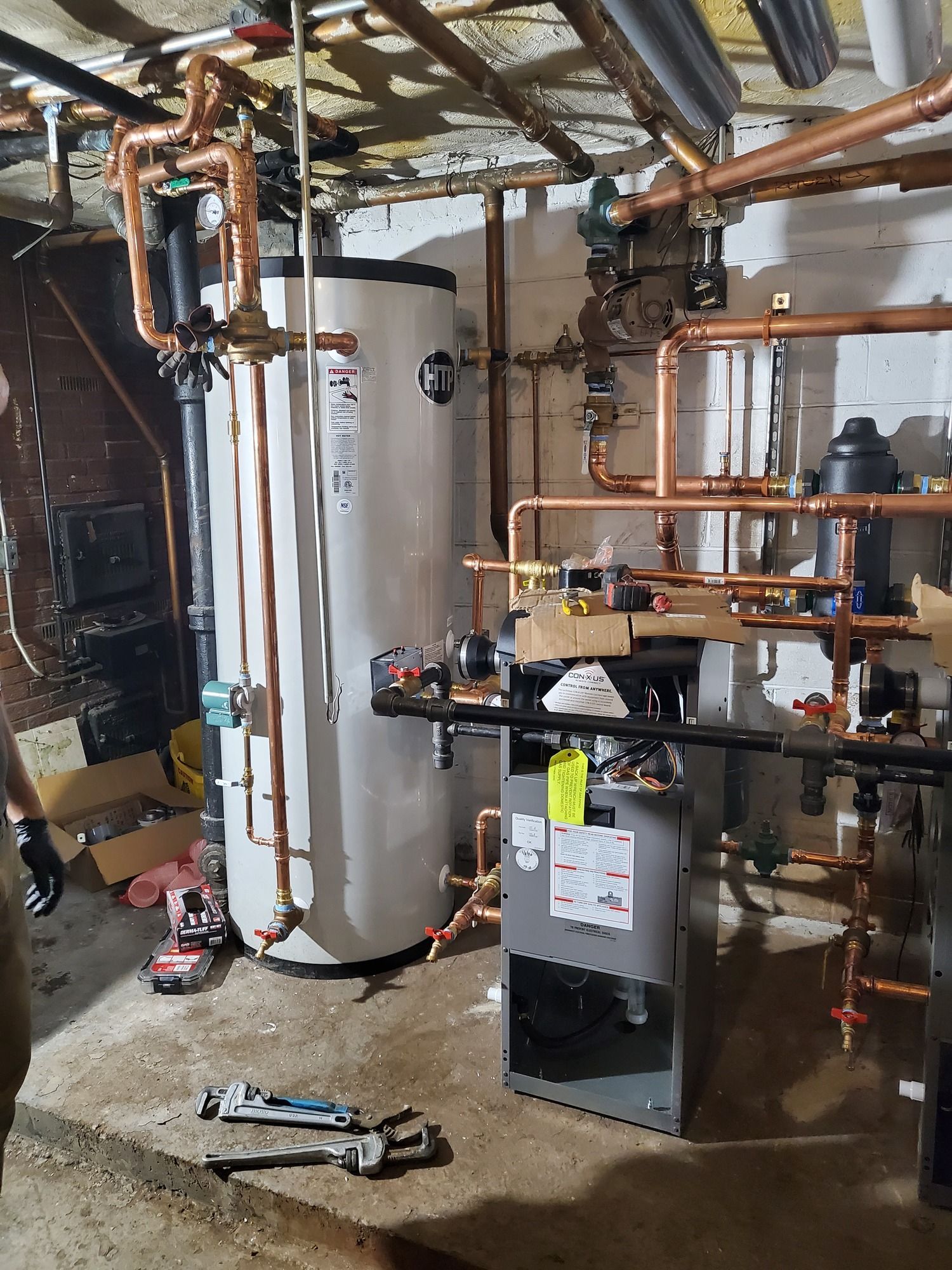 A man is working on a water heater in a basement.