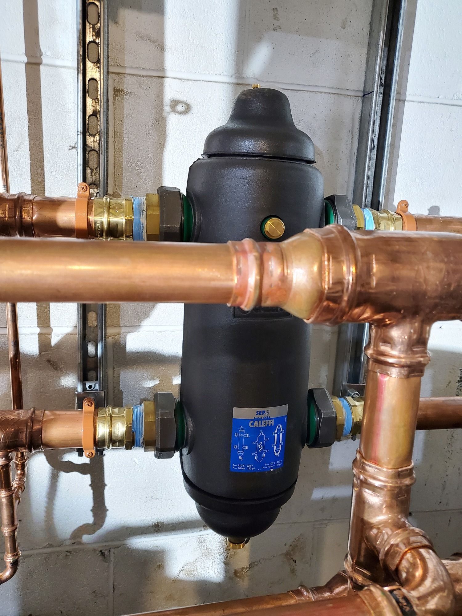 A copper pipe with a black container attached to it.