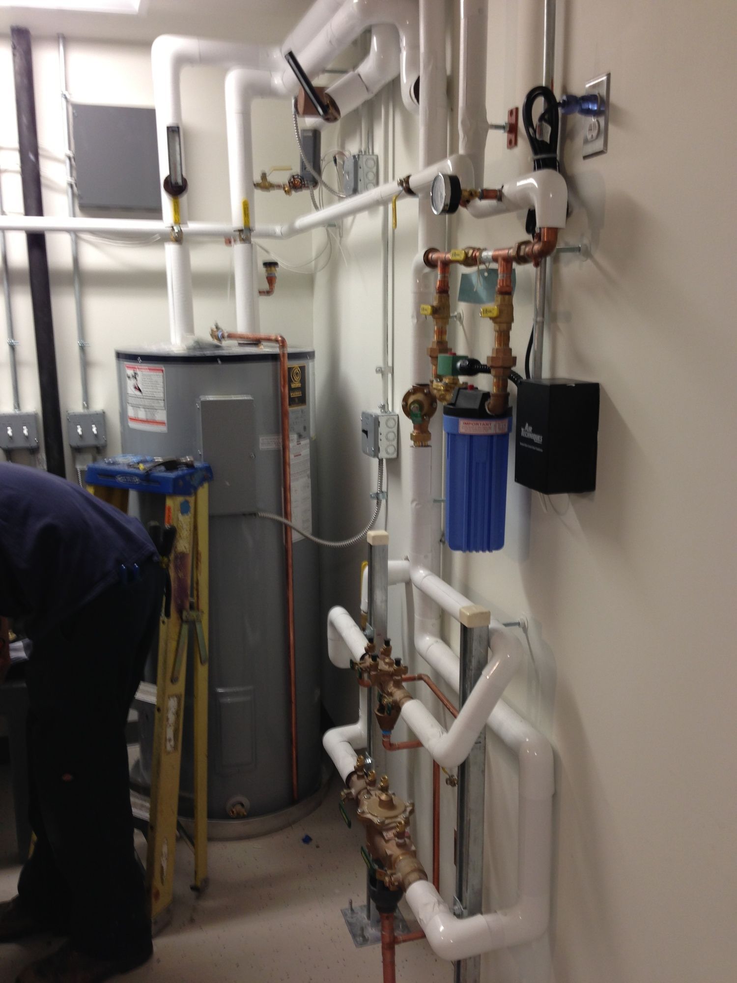 A man is working on a water heater in a basement