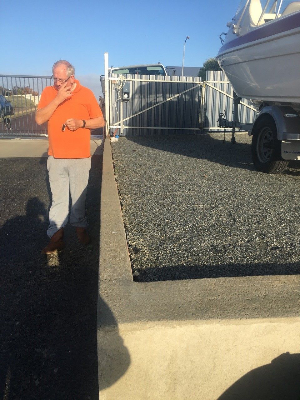 A man in an orange shirt is standing next to a boat