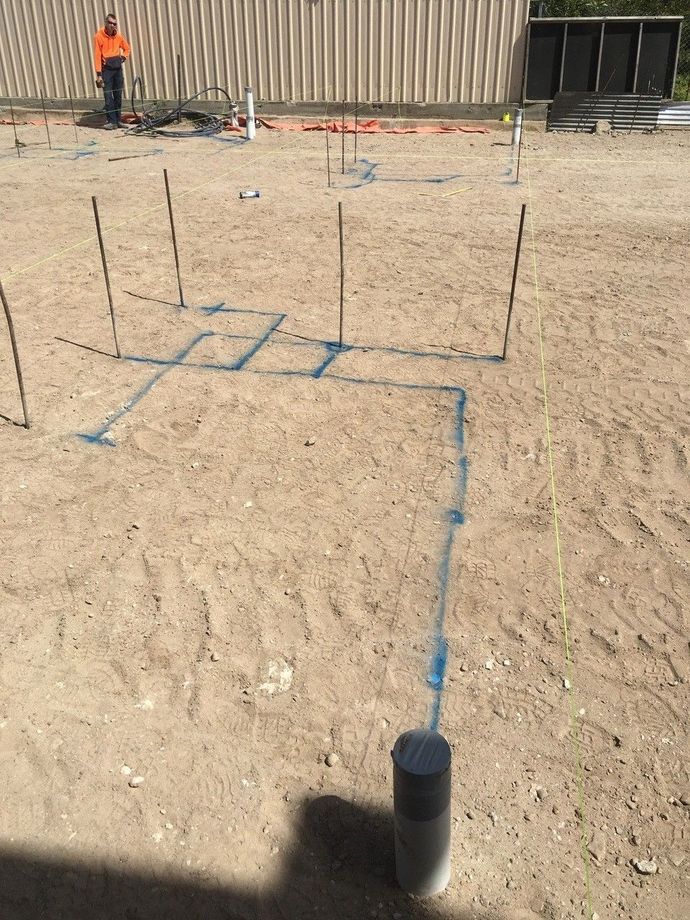 A man in an orange vest is standing on a dirt field