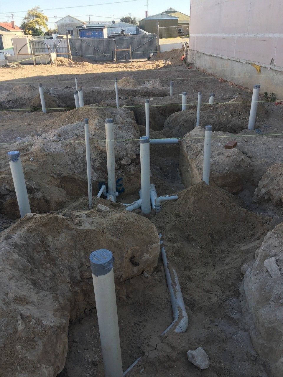 A bunch of pipes are laying in the dirt