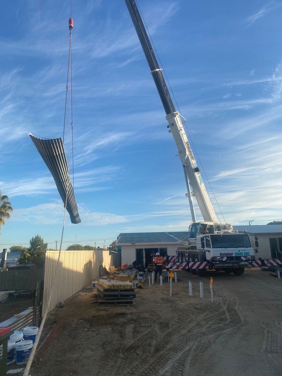 A large crane is lifting a large piece of metal on a construction site.