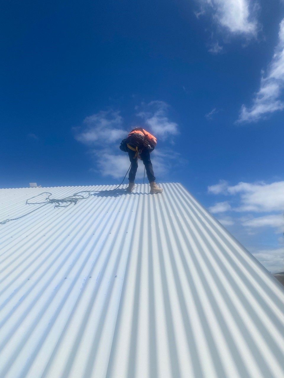 A man is standing on top of a white roof