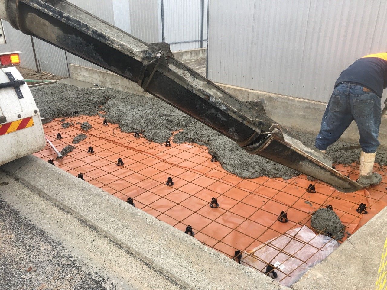 A man is pouring concrete into a hole in the ground.
