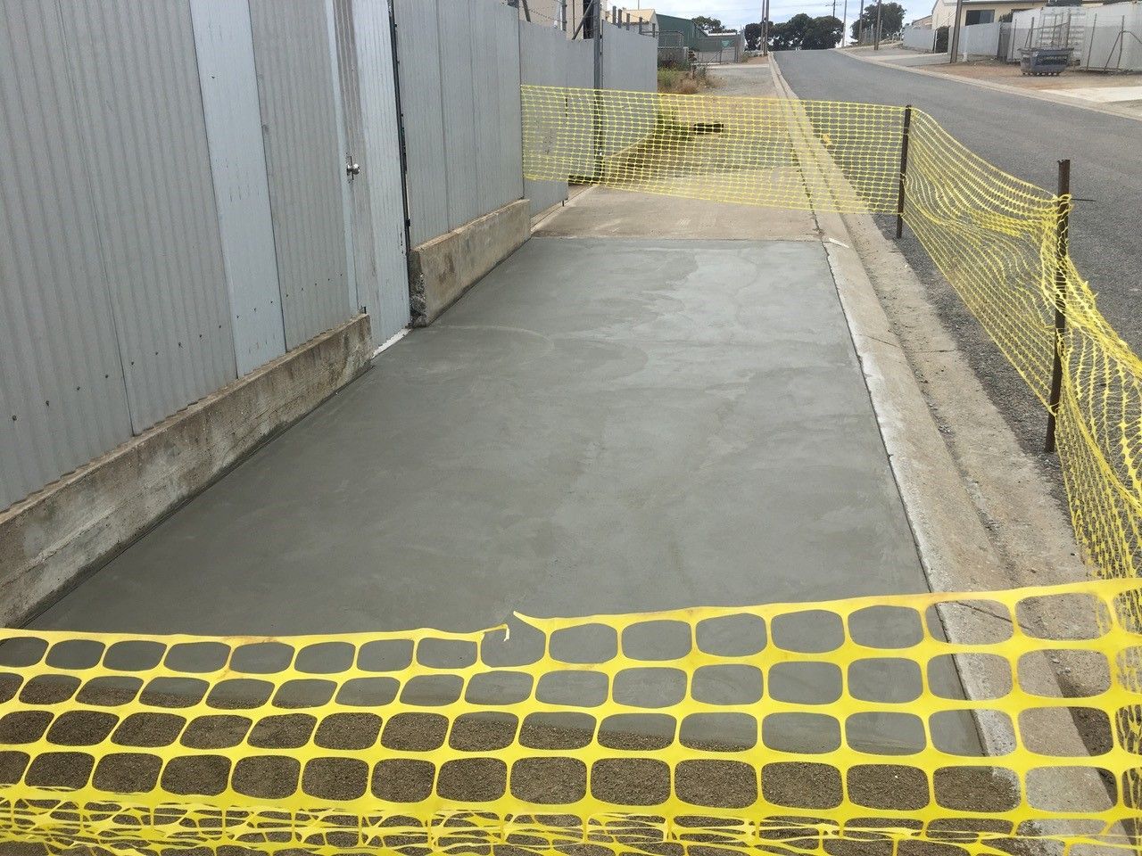 A yellow fence is surrounding a concrete walkway