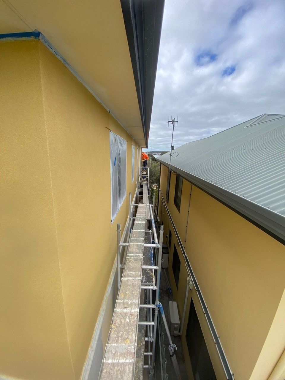A ladder is being used to paint the side of a building.
