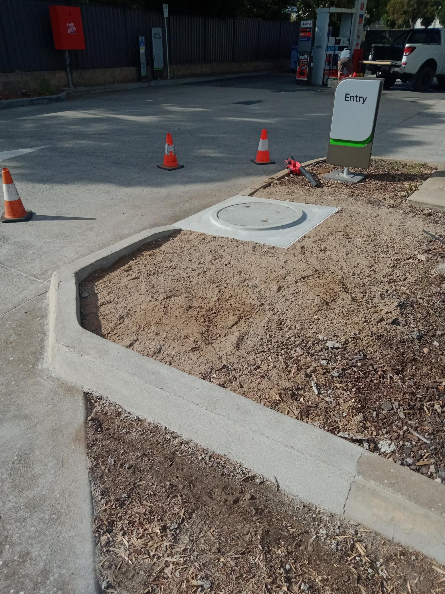A concrete curb with a manhole cover in the middle of it