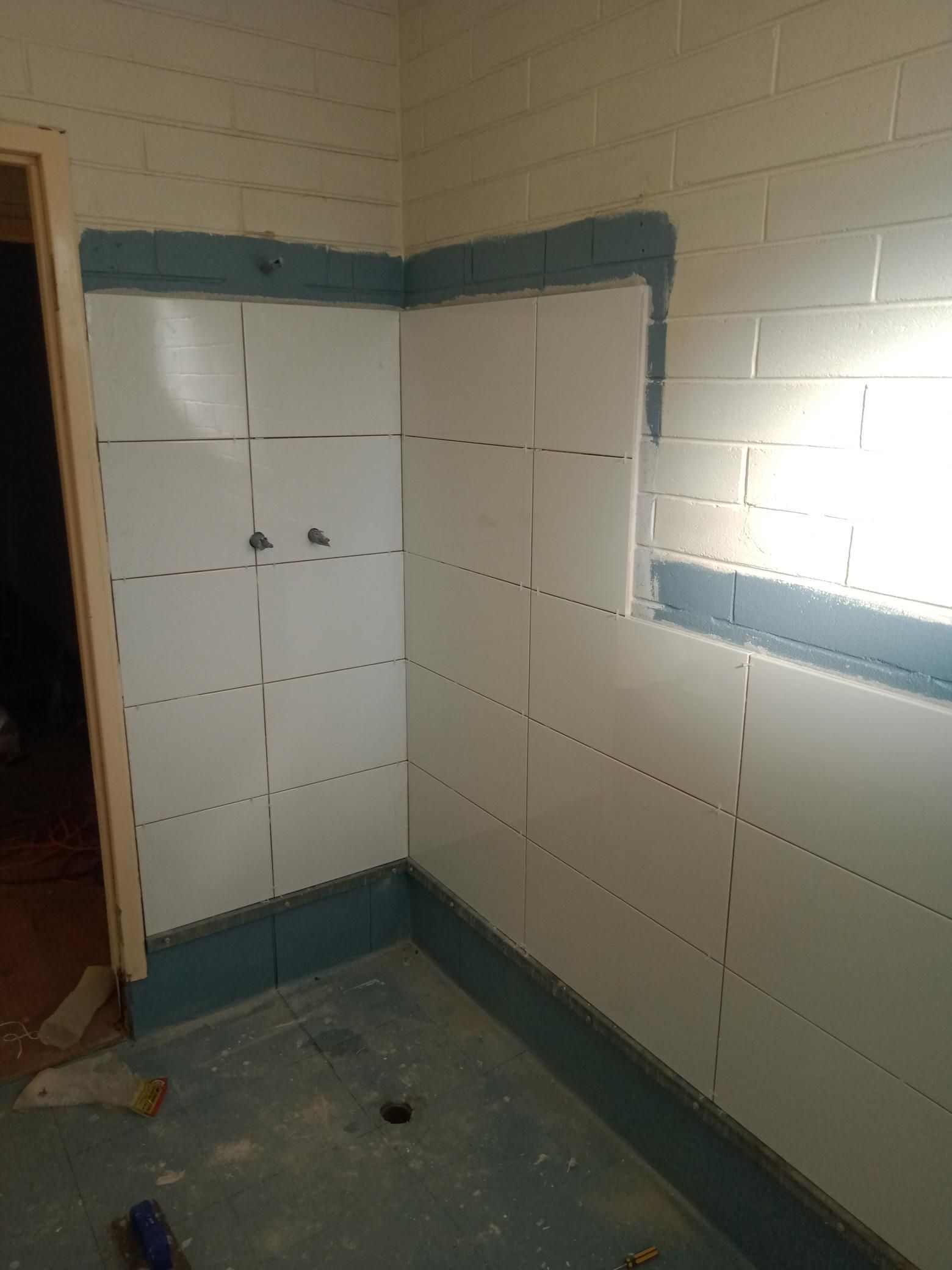 A bathroom with white tiles and blue trim is being remodeled.