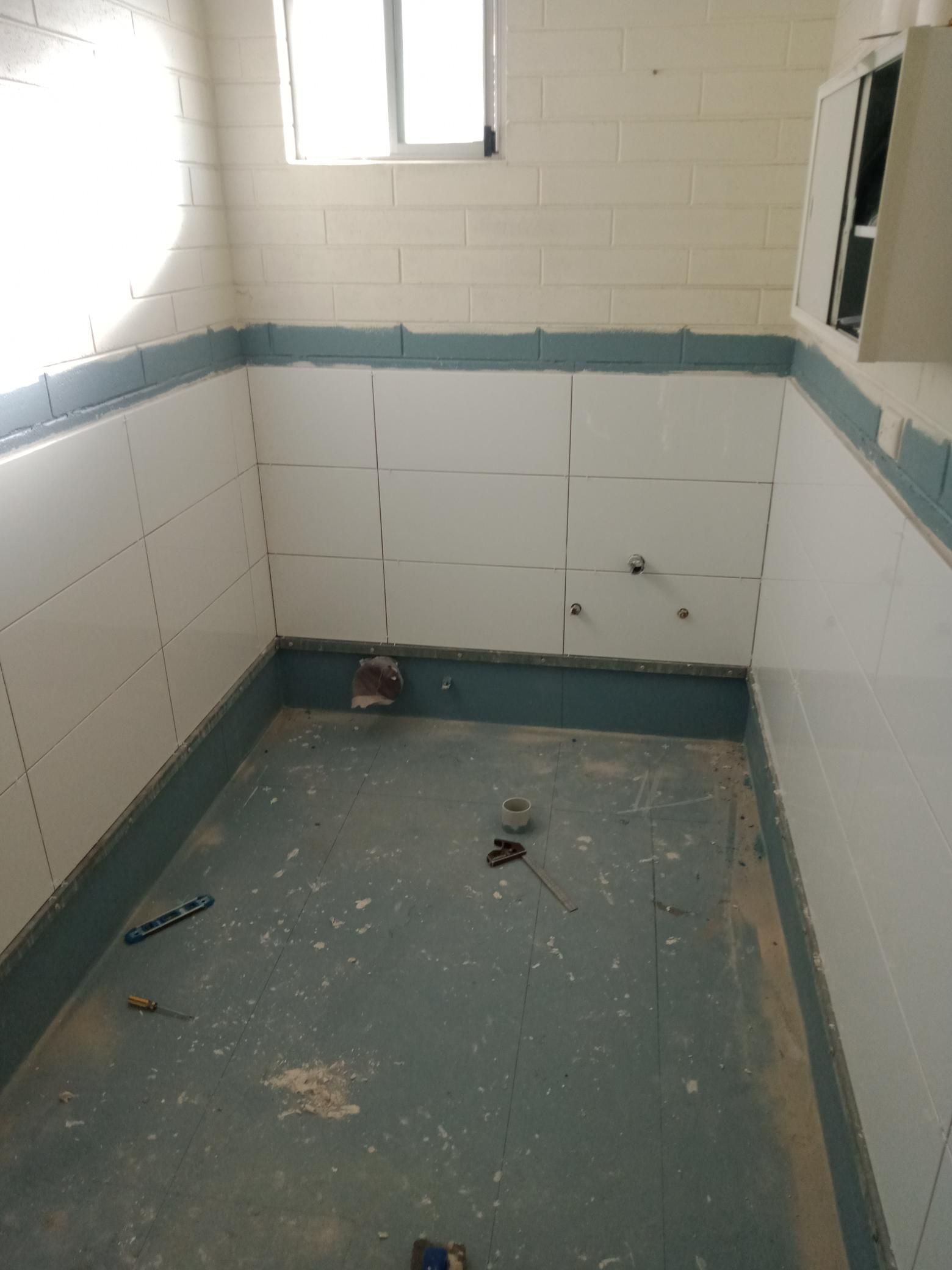 A bathroom with white tiles and blue trim is being remodeled.