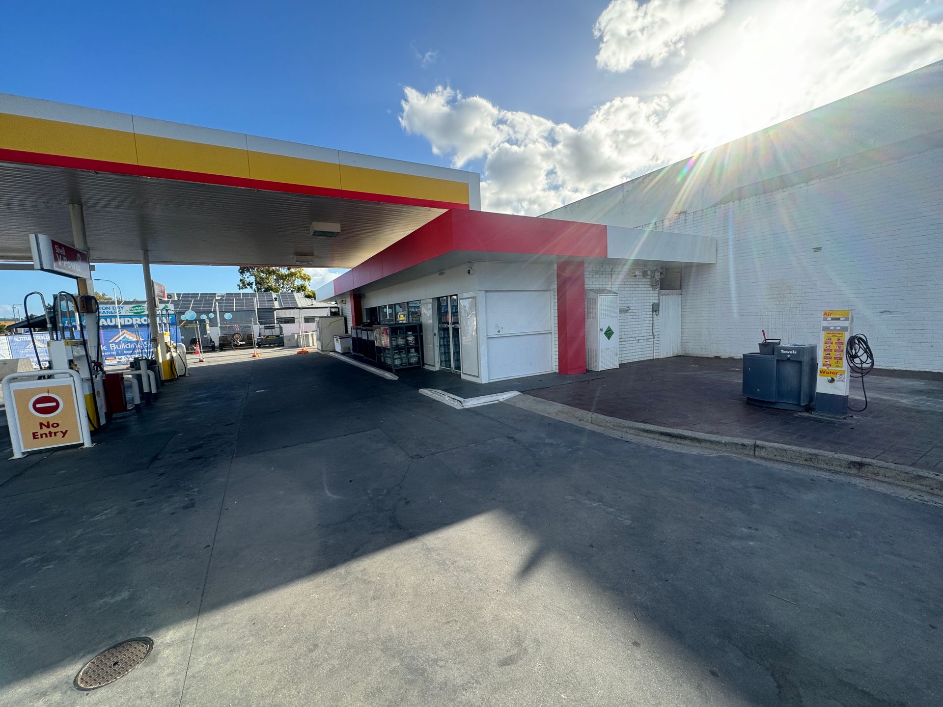 A gas station with a red roof and a white building in the background.