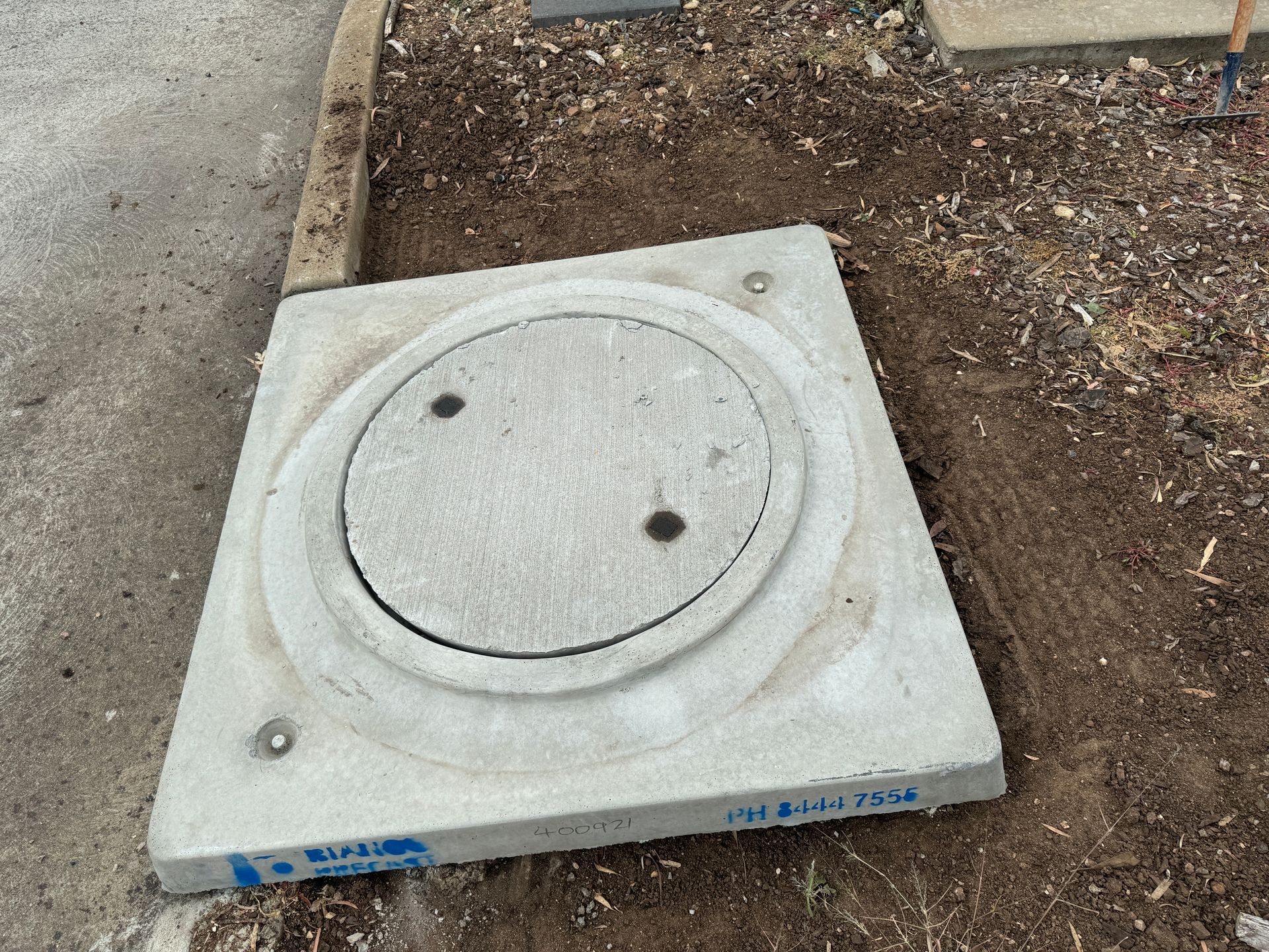 A concrete manhole cover is sitting on the ground.