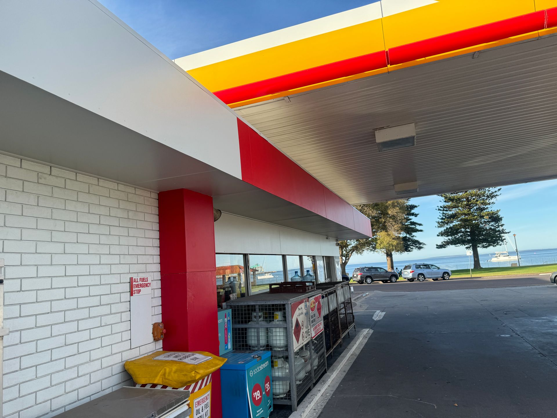 A gas station with a brick wall and a red and yellow roof.