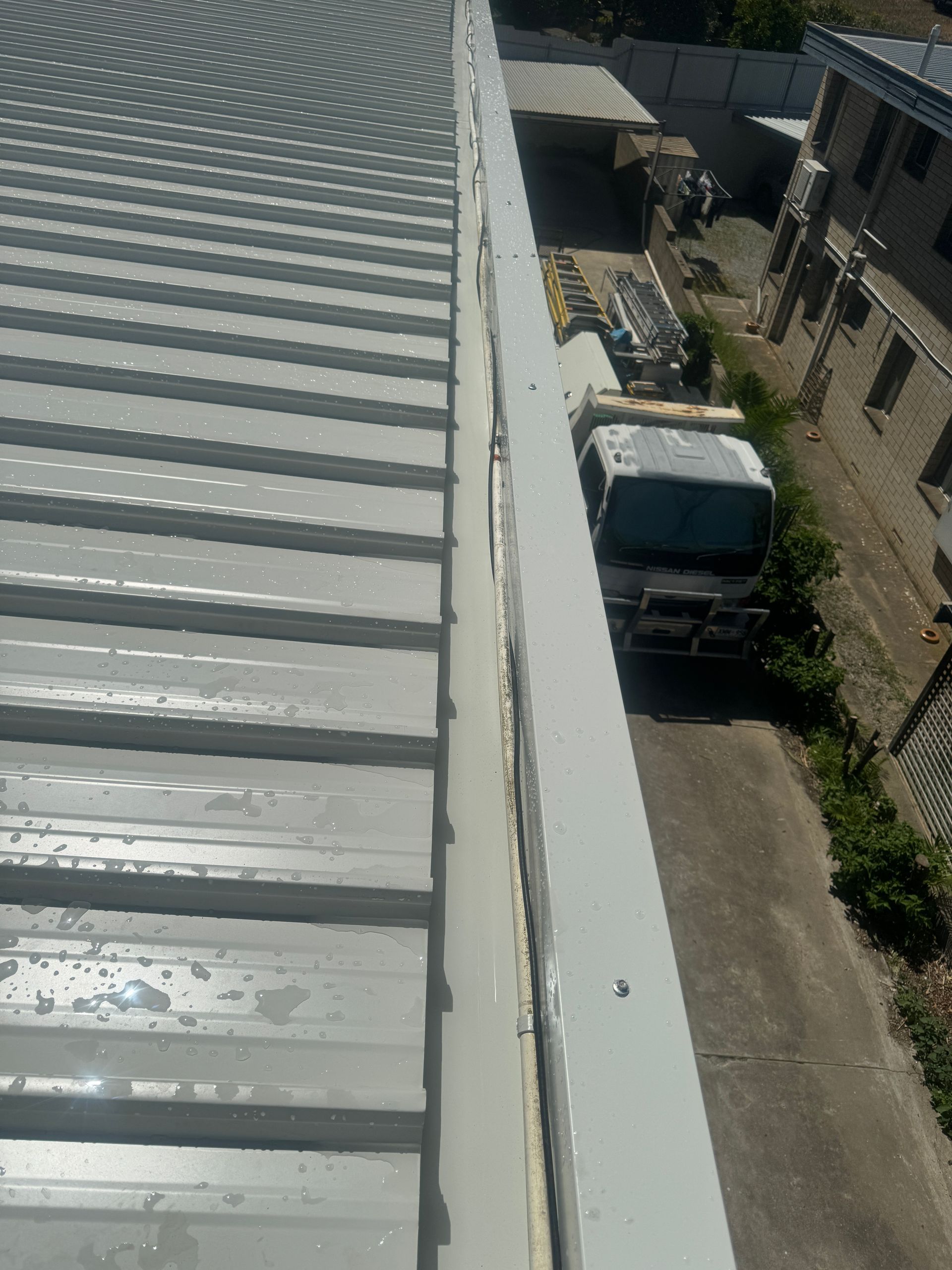 A truck is parked on the side of a building next to a roof.
