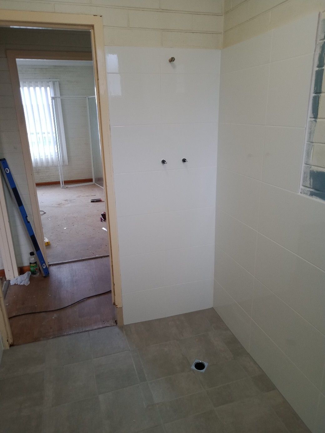 A bathroom with a shower stall and a door leading to a room.