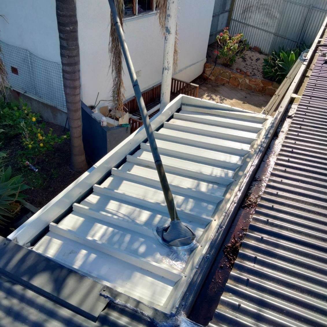 A mop is sitting on top of a metal roof.