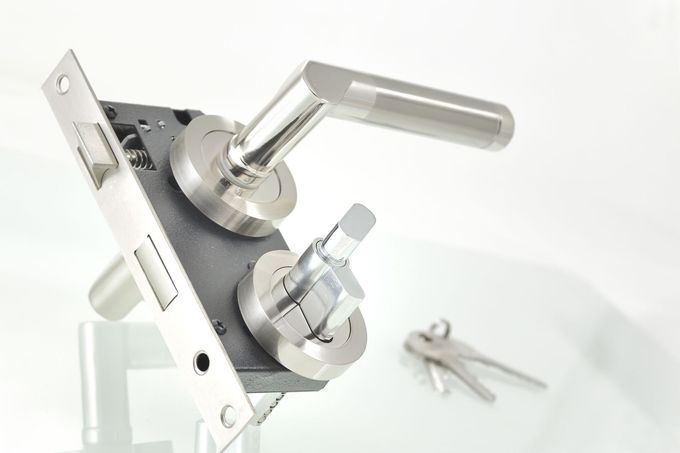 Serratura per porta color argento con maniglia e chiavistello, su sfondo bianco.