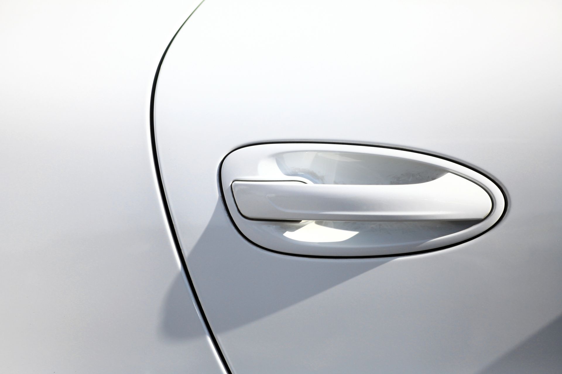 Una maniglia bianca per portiera d'auto montata su un pannello della carrozzeria bianco abbinato.