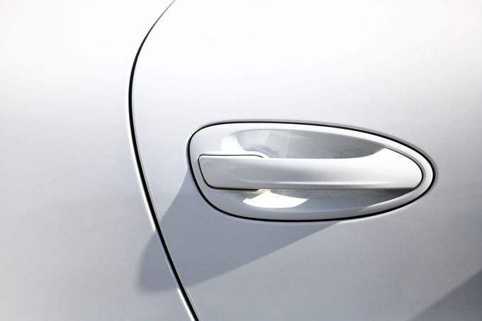 Vista ravvicinata di una maniglia bianca della portiera di un'auto, integrata nel pannello liscio e curvo del veicolo.
