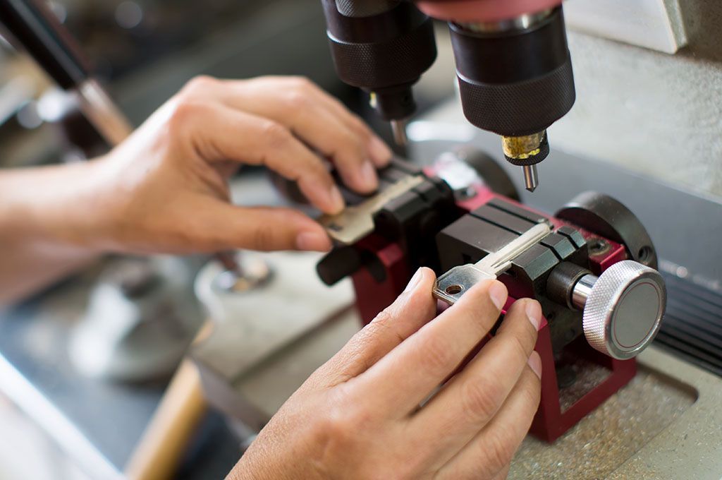 Una persona utilizza una macchina duplicatrice di chiavi per riprodurre una chiave metallica.