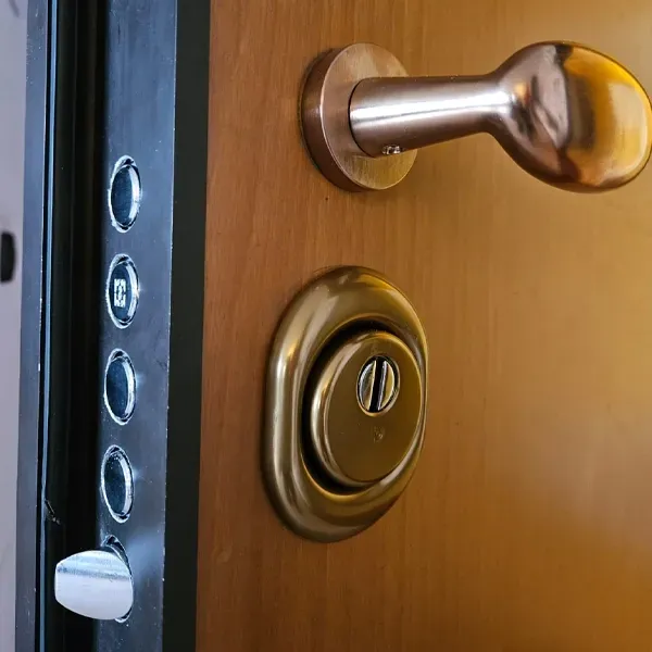 Primo piano di una macchina duplicatrice di chiavi in metallo con struttura arancione e blu scuro, che mostra una chiave tenuta in una morsa metallica.