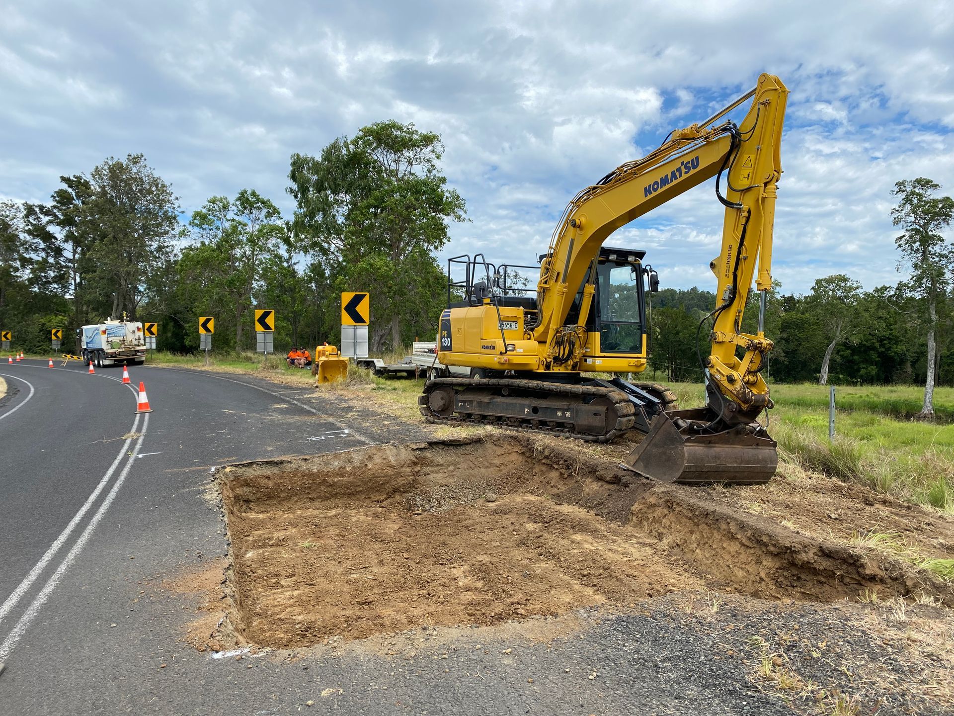 A Yellow Komatsu Excavator Digs a Trench on the Side of a Road — PVM Contracting in Alstonville, NSW