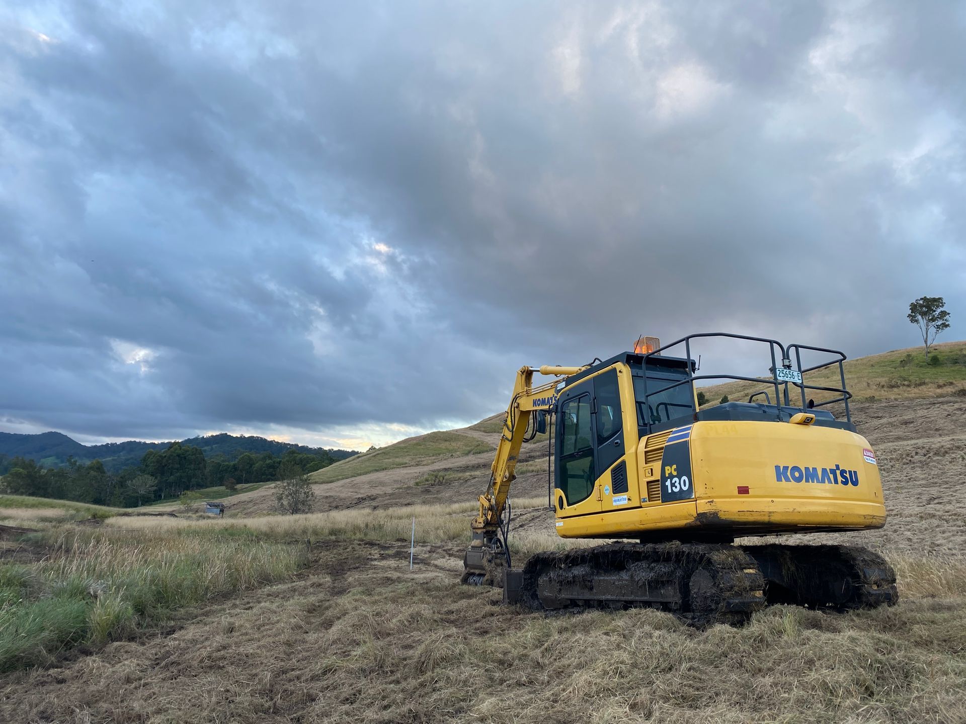 A Yellow Komatsu Excavator on a Hillside — PVM Contracting in Mullumbimby, NSW