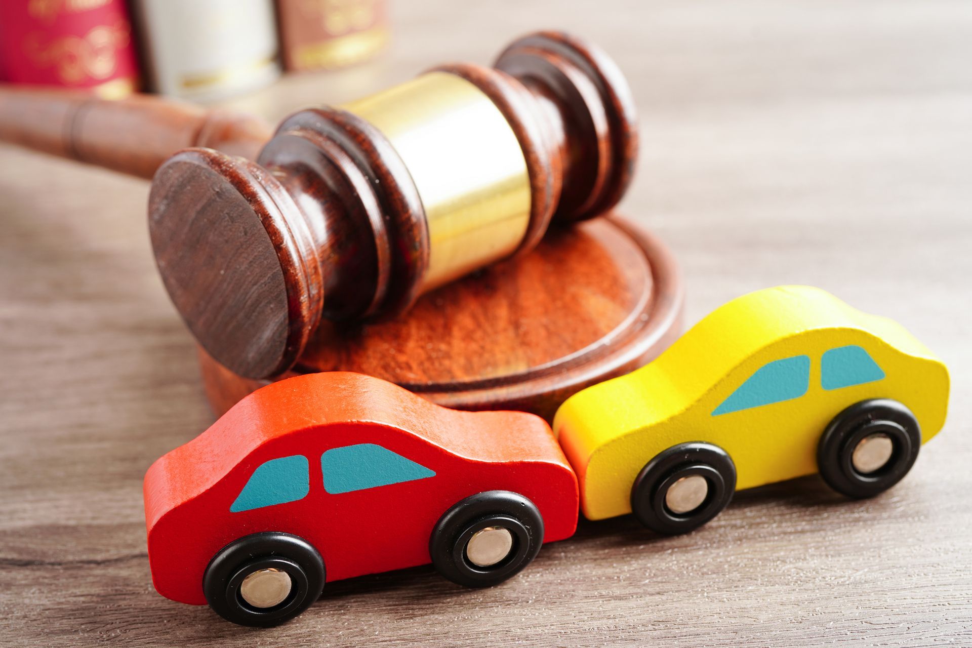 Two miniature cars simulating a crash and a wooden gavel on top of the car accident attorney’s table Two miniature cars simulating a crash and a wooden gavel on top of the car accident attorney’s table