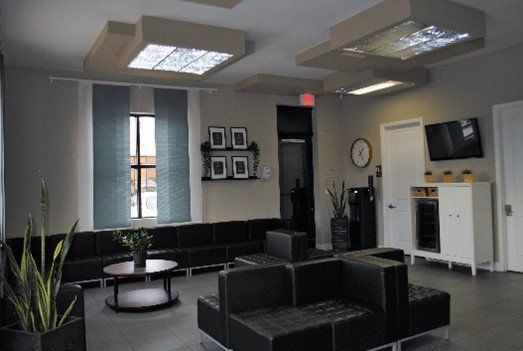 A waiting room with black furniture and a clock on the wall | United Critical Care