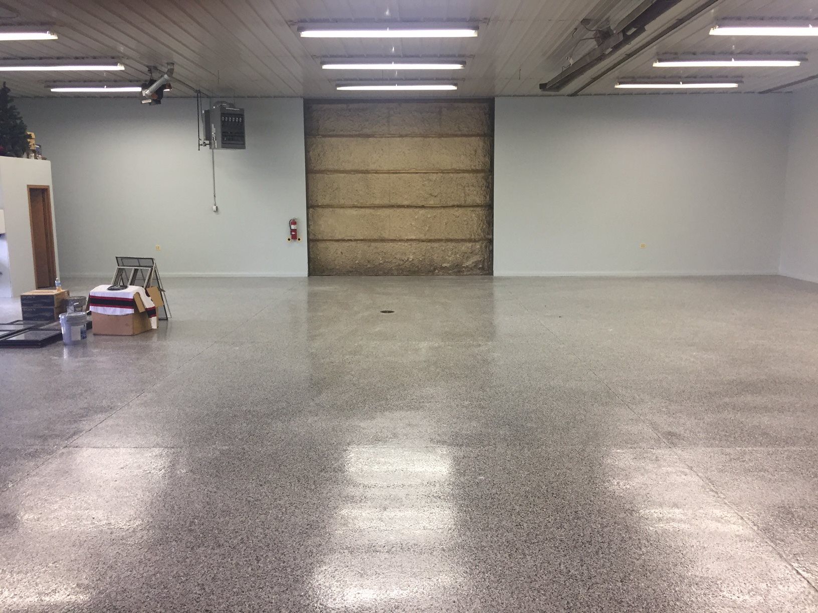 a large empty room with a garage door in the background .