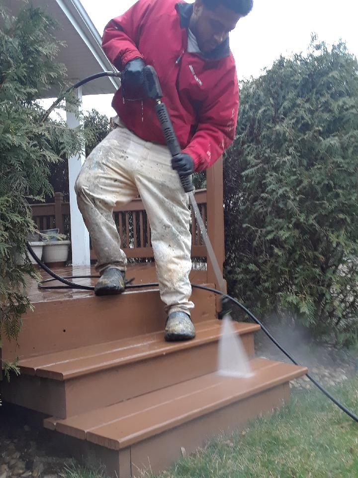 a man in a red jacket is using a high pressure washer to clean stairs .