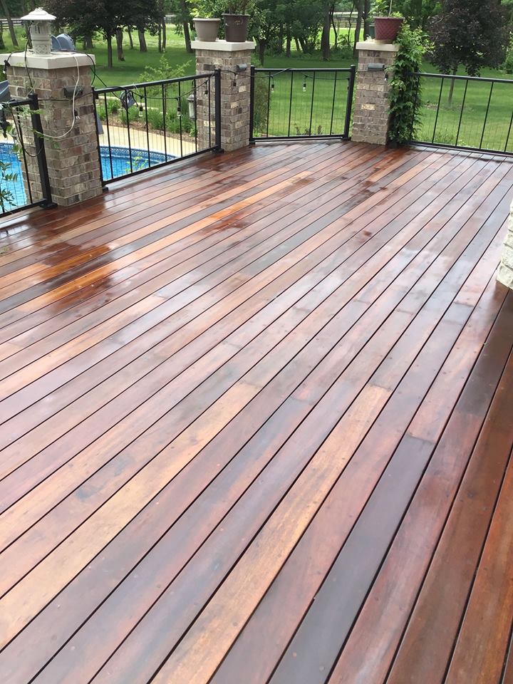 a wooden deck with a railing and a pool in the background .