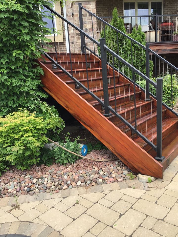 a wooden staircase with a metal railing is leading up to a deck .
