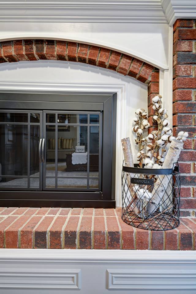 a fireplace with a glass door and a brick wall in a living room .