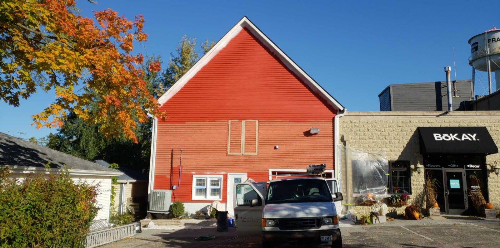 a white van is parked in front of a red barn .