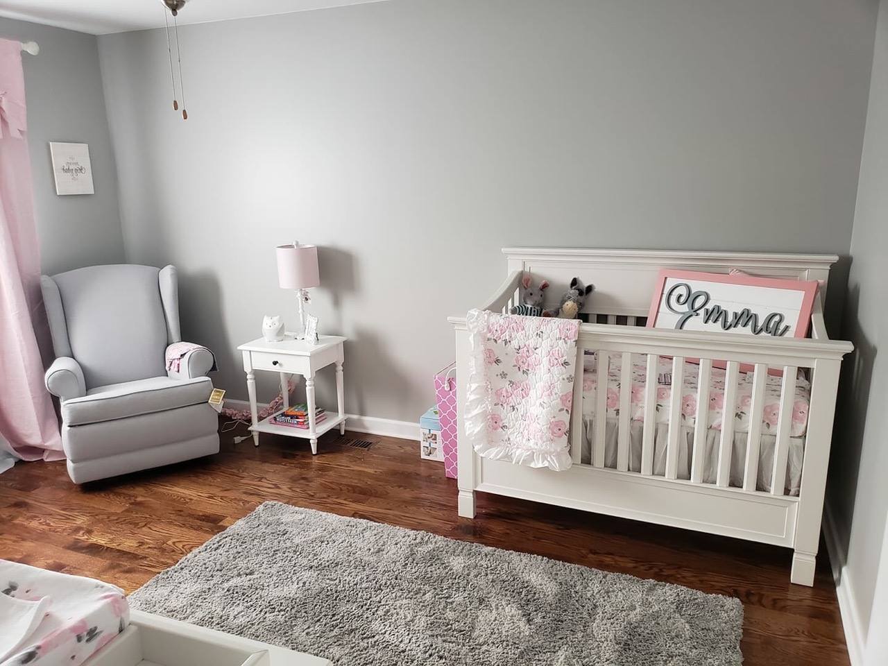 a baby girl 's nursery with a crib , chair , and rug .
