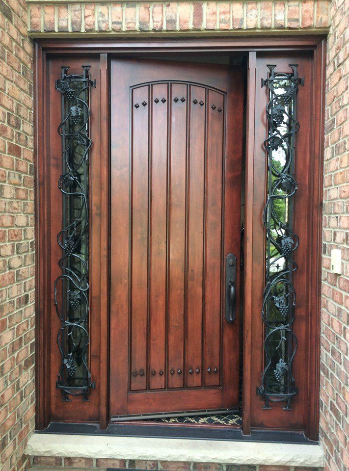 a wooden door with a wrought iron frame is on a brick building .