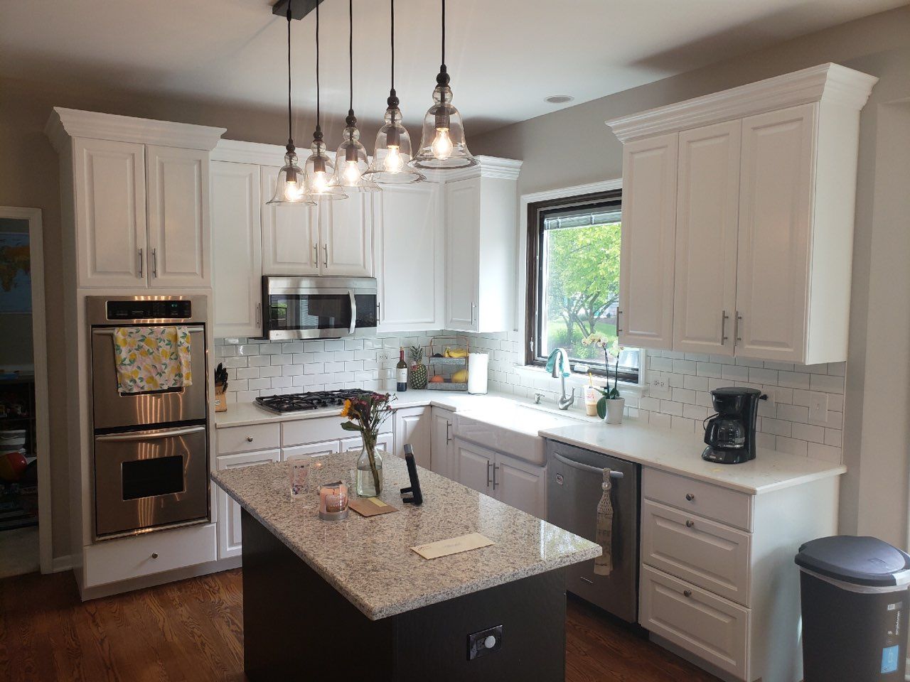 a kitchen with white cabinets , granite counter tops , stainless steel appliances and a large island .