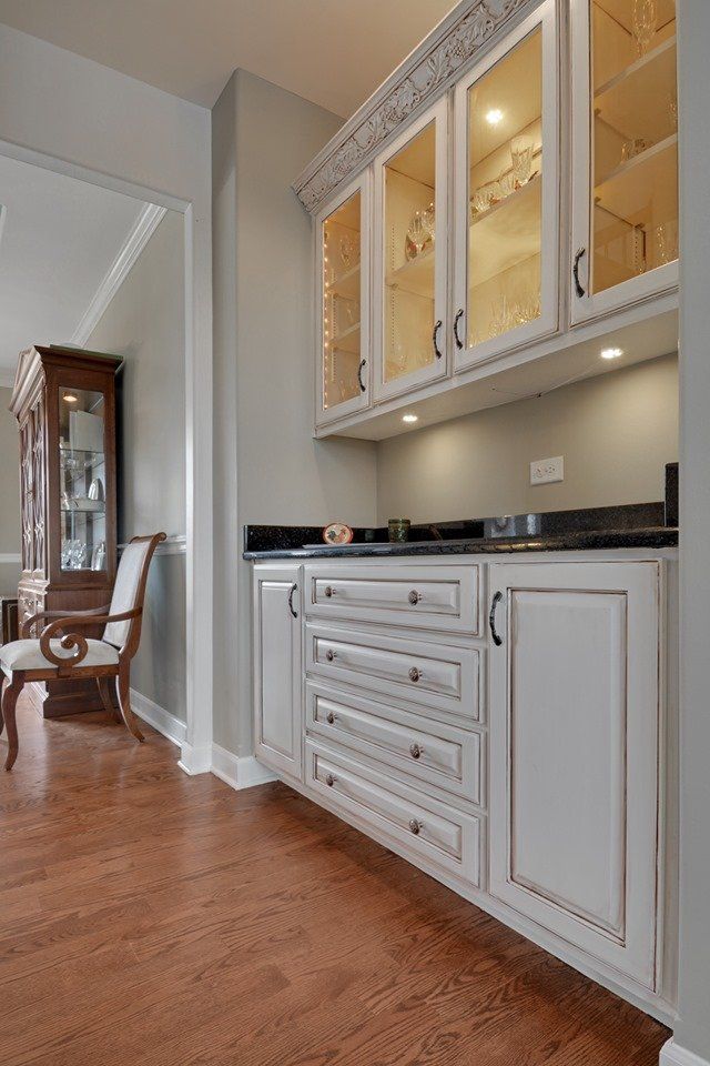 a kitchen with white cabinets and glass doors and a dining room in the background .