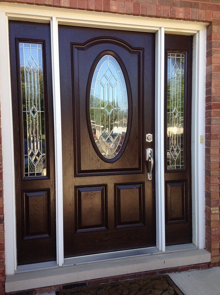 a brown door with a stained glass window is on a brick building .
