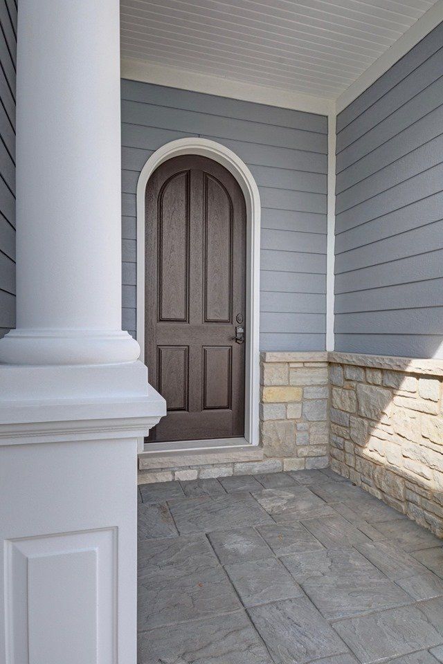 a porch with a brown door and a white column .