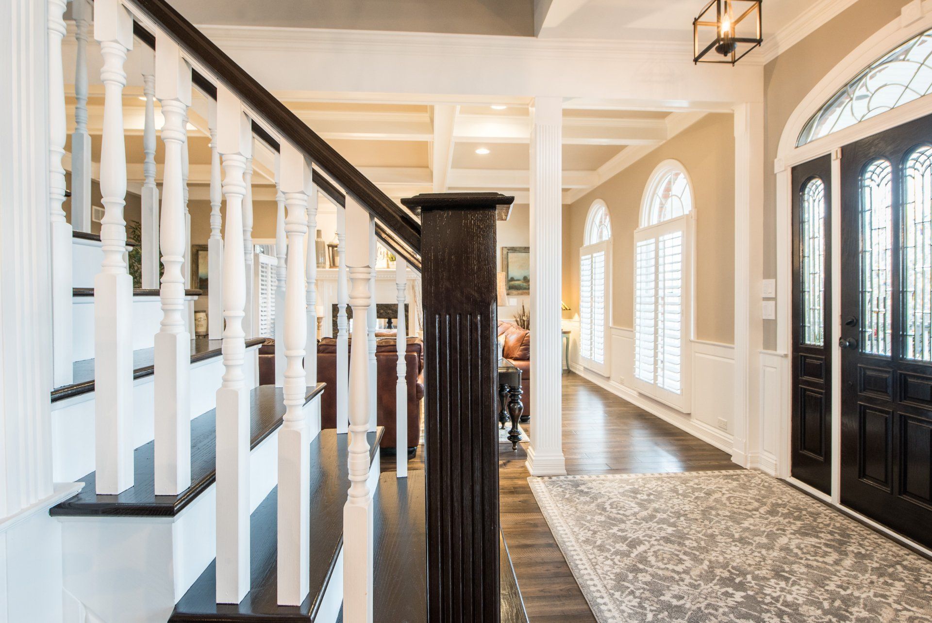 a hallway with stairs leading up to a living room and a black door .