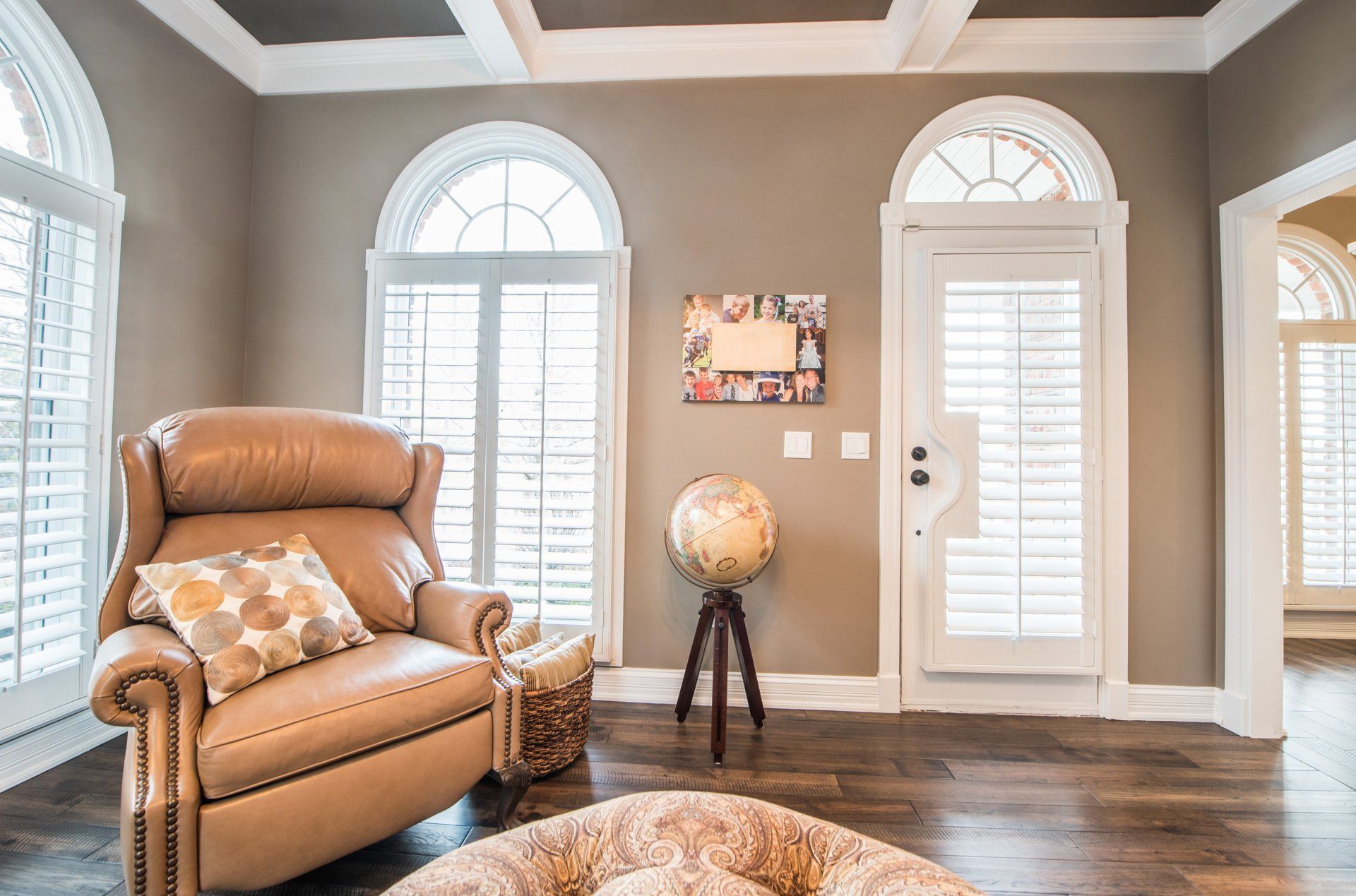 a living room with a recliner , globe , and shutters .