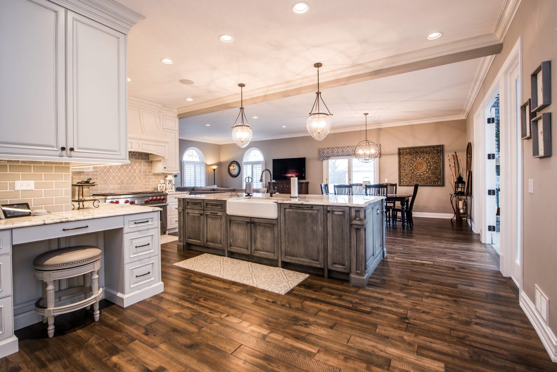 a kitchen with hardwood floors , white cabinets and a large island .