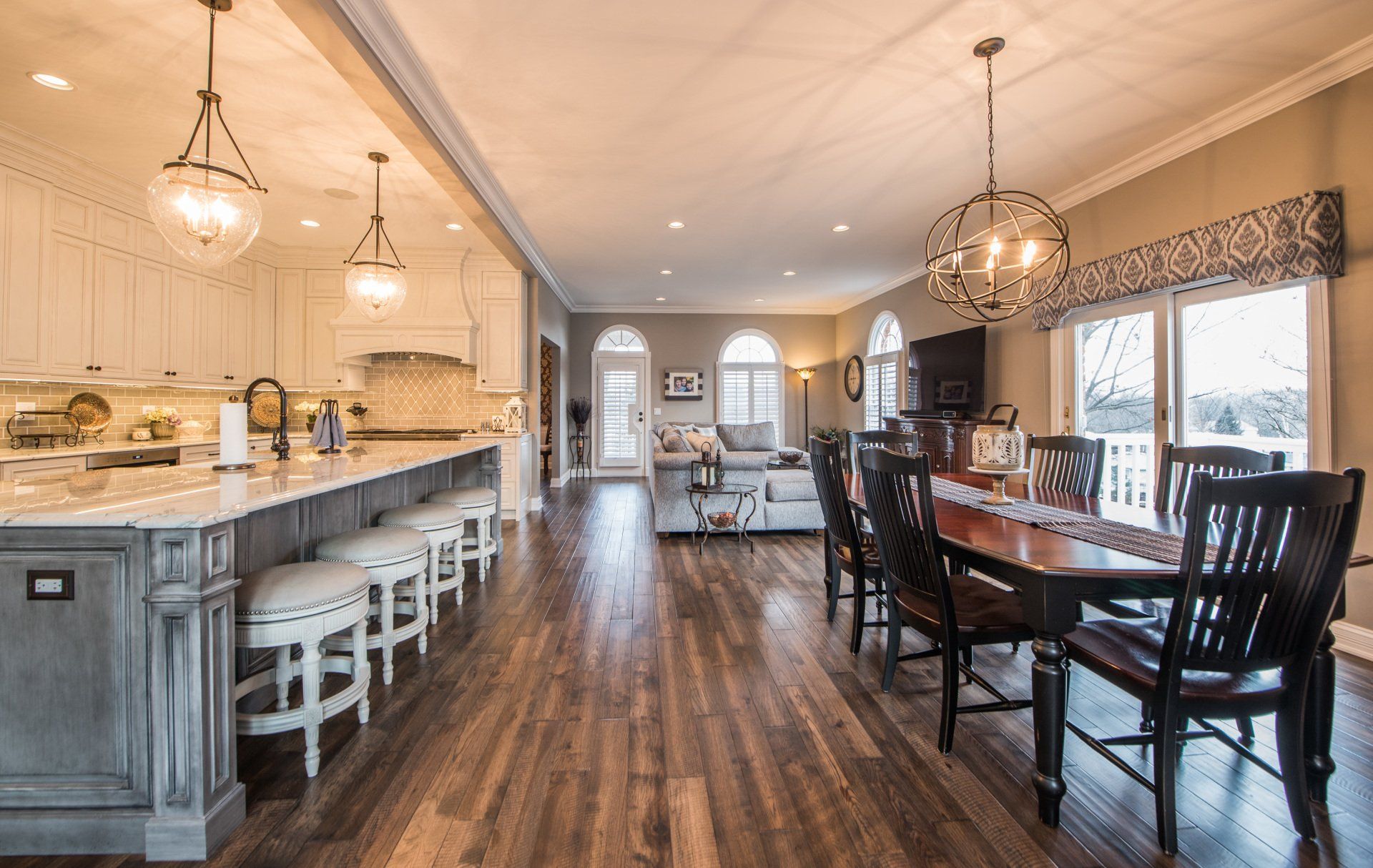 a kitchen , dining room and living room in a house with hardwood floors .