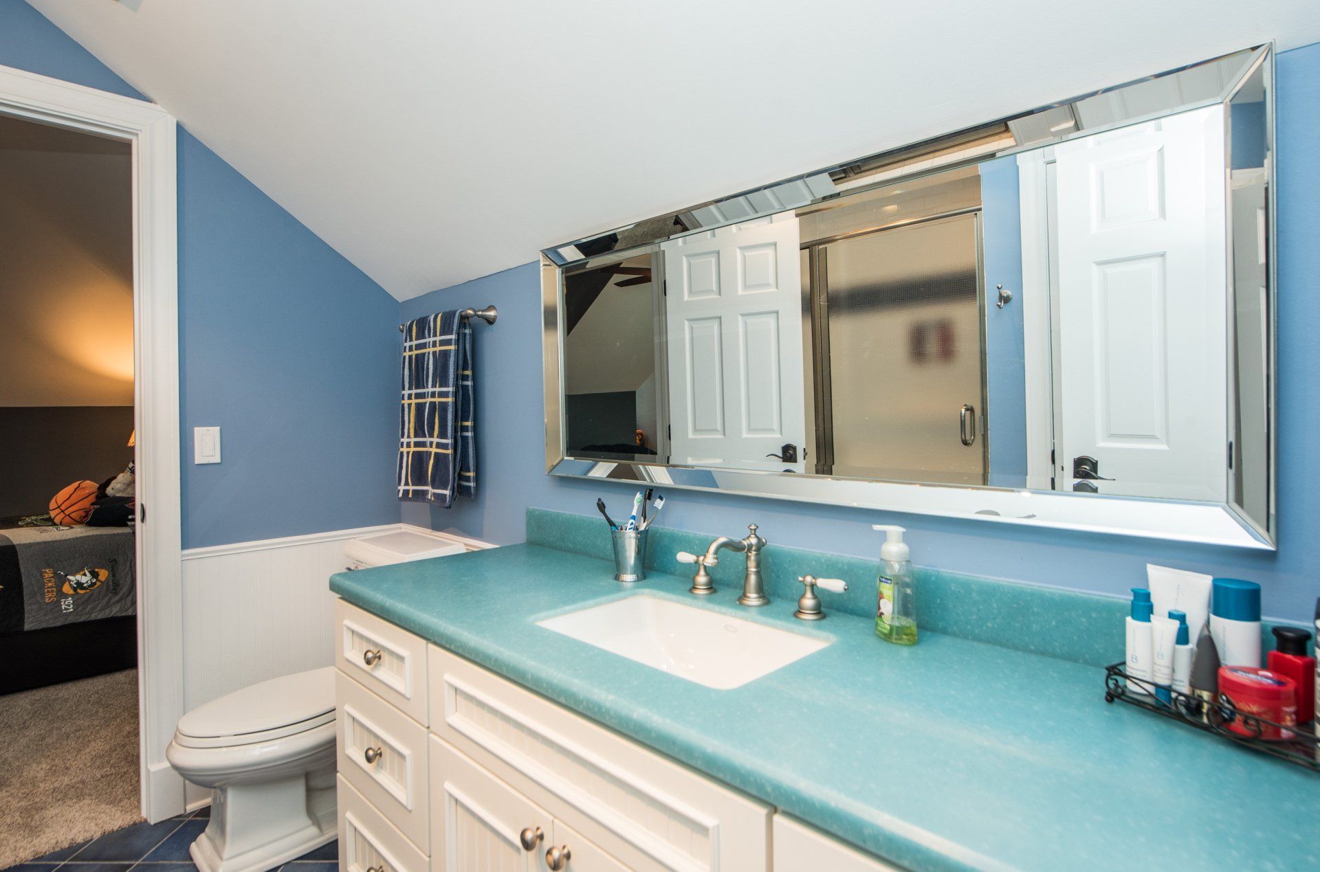 a bathroom with a toilet , sink , mirror and blue counter top .