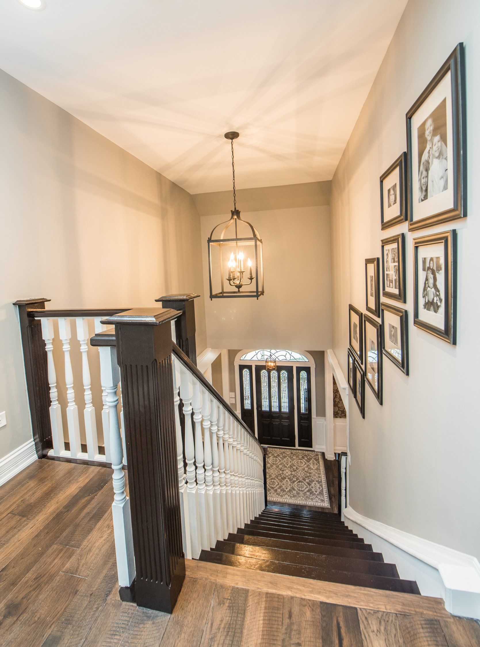 a staircase in a house with pictures on the wall and a lantern hanging from the ceiling .