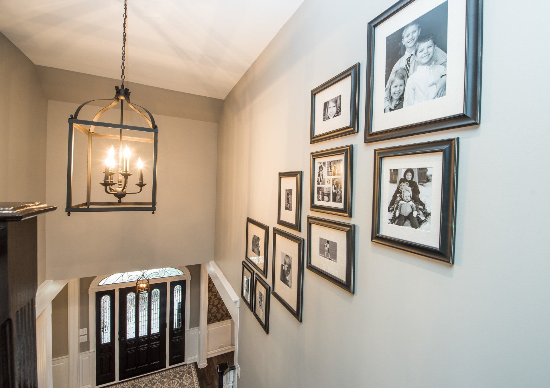 a staircase with pictures on the wall and a chandelier hanging from the ceiling .