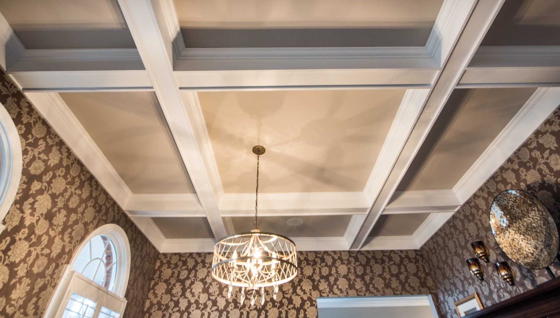a chandelier is hanging from the ceiling of a room with a coffered ceiling .